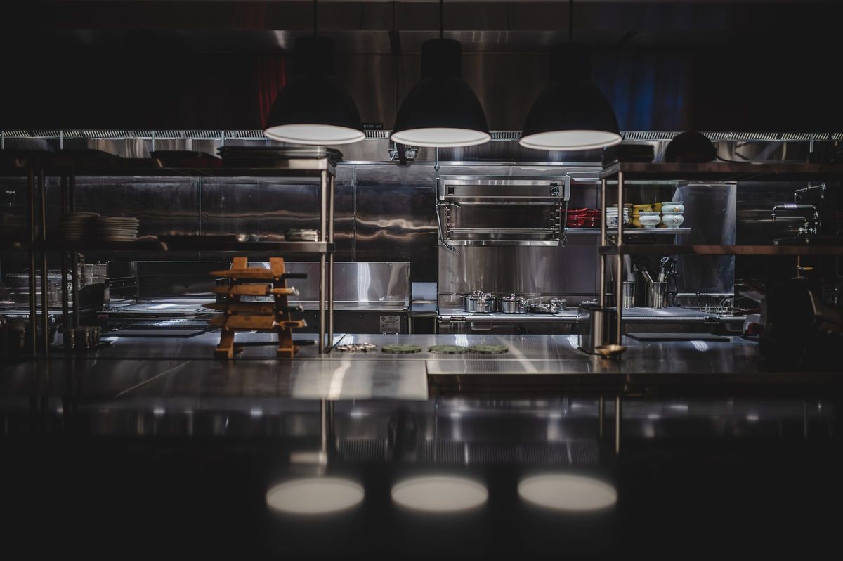Open kitchen in brushed stainless under three black pendants, Jeju Noodle Bar.