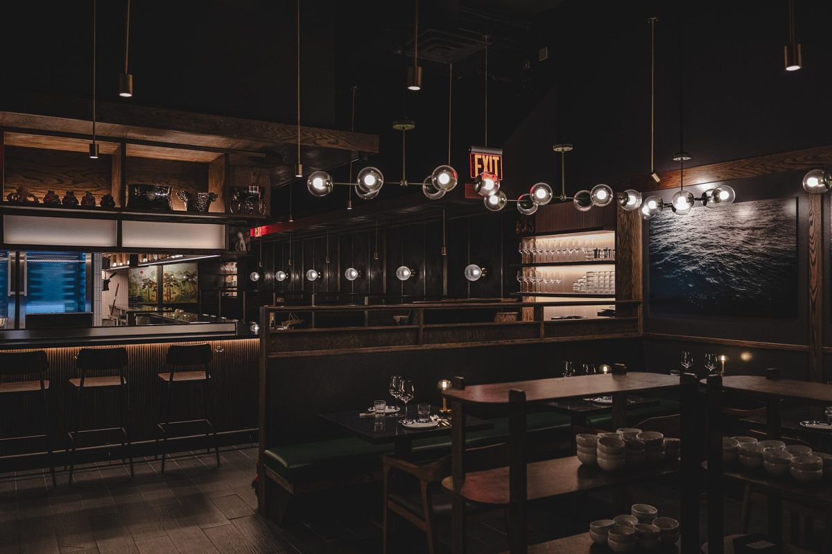 Dining room and bar with a fluted timber bar front, built-in shelving, banquettes and strings of glass globe pendants, Jeju Noodle Bar.