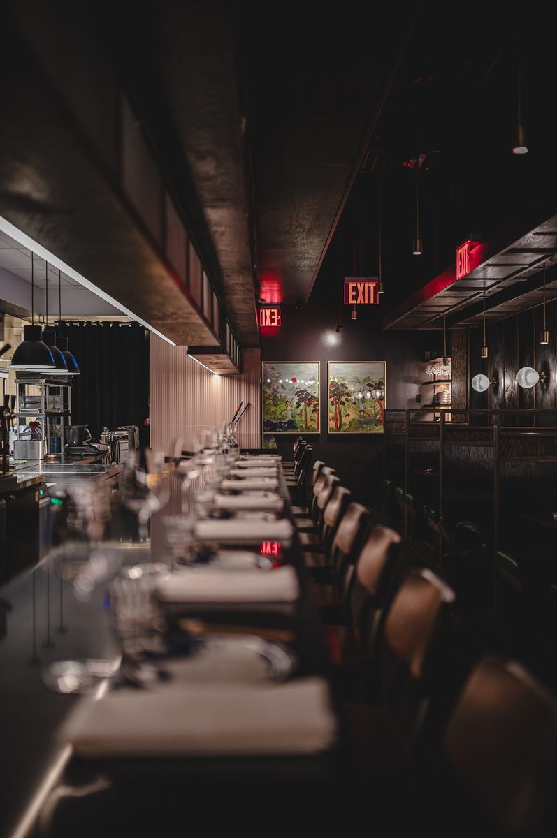 Long counter set with linen napkins and glassware, looking toward the back wall, Jeju Noodle Bar.